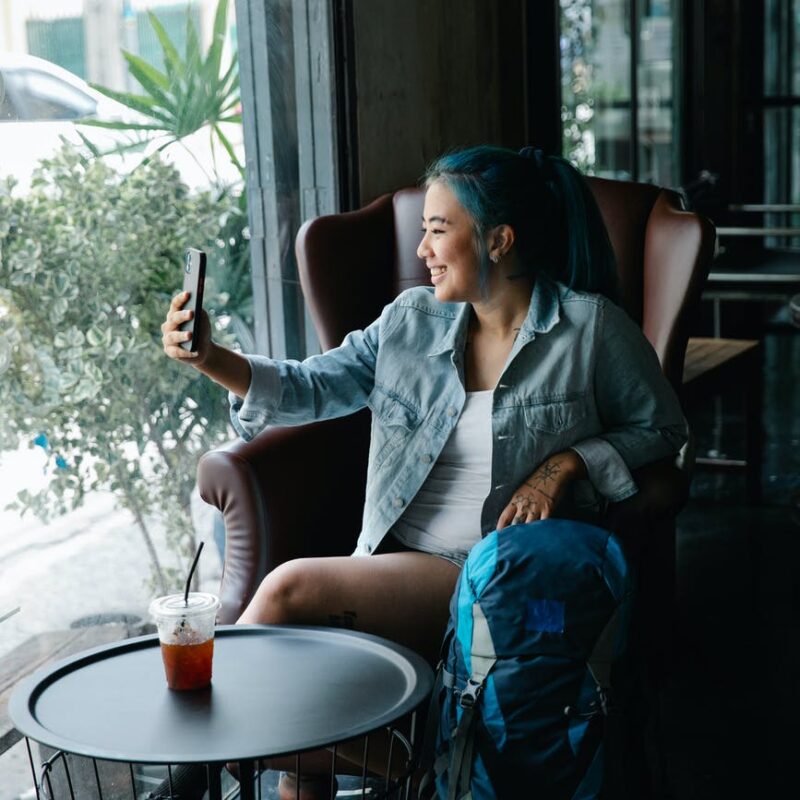 delighted asian woman taking selfie at table